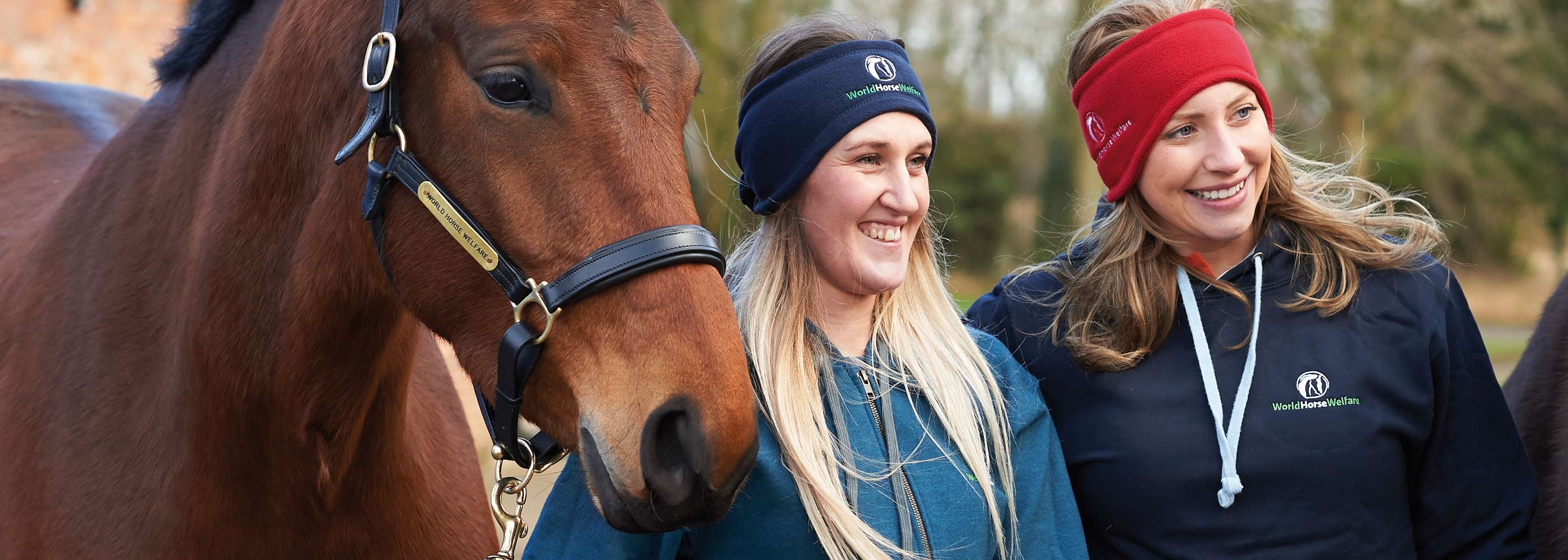 Two women dressed in WHW attire leading their horses